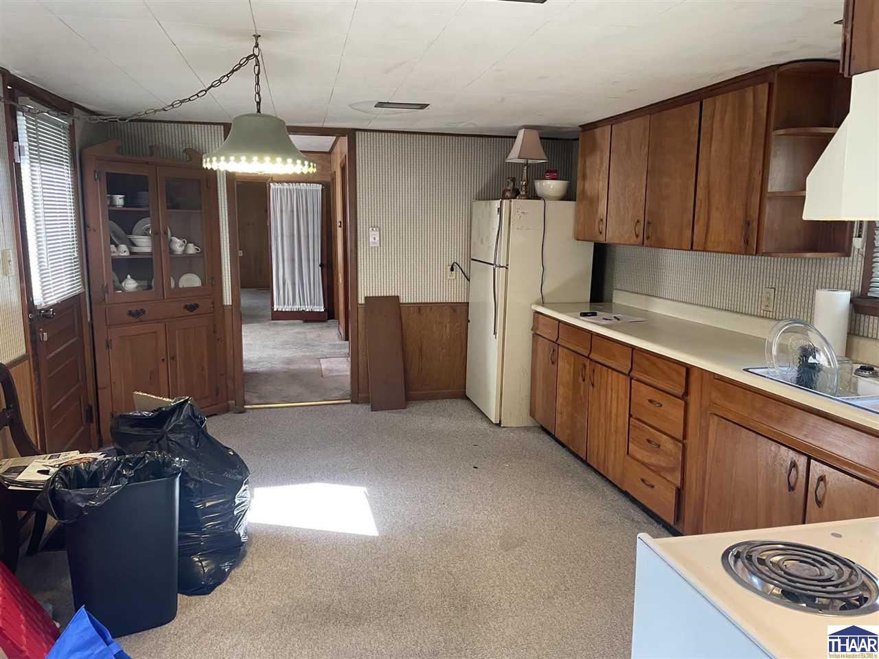 Kitchen with wood cabinets, white appliances, and a glass-front china cabinet.