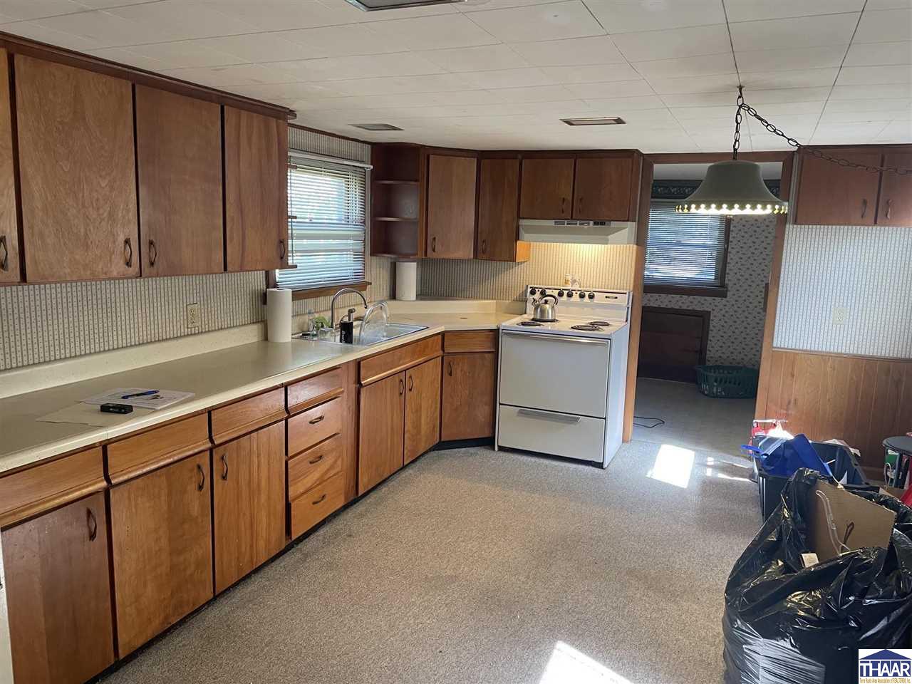 Kitchen with wood cabinets, cream countertops, and a white electric range.