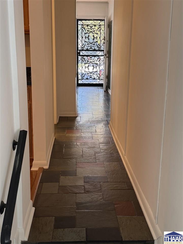 Hallway with multicolored slate flooring and a decorative wrought-iron glass door.