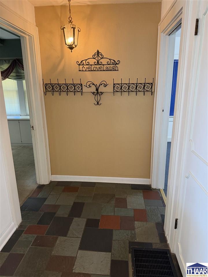 Entry hall with multicolored slate tile flooring, iron wall décor, and a hanging lantern.
