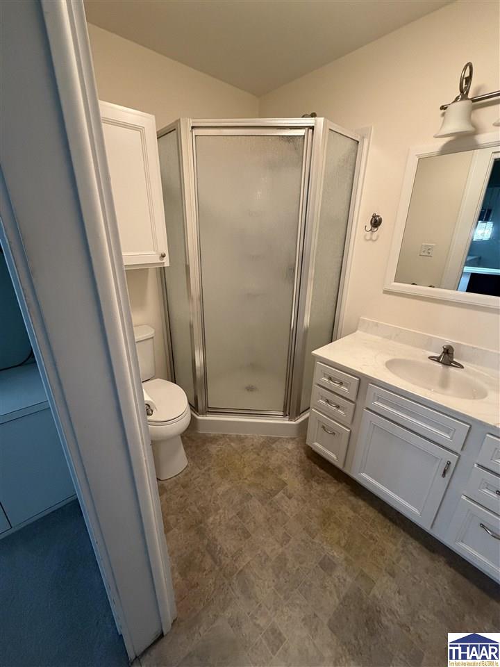 Bathroom with a frosted-glass corner shower, toilet, and white vanity.