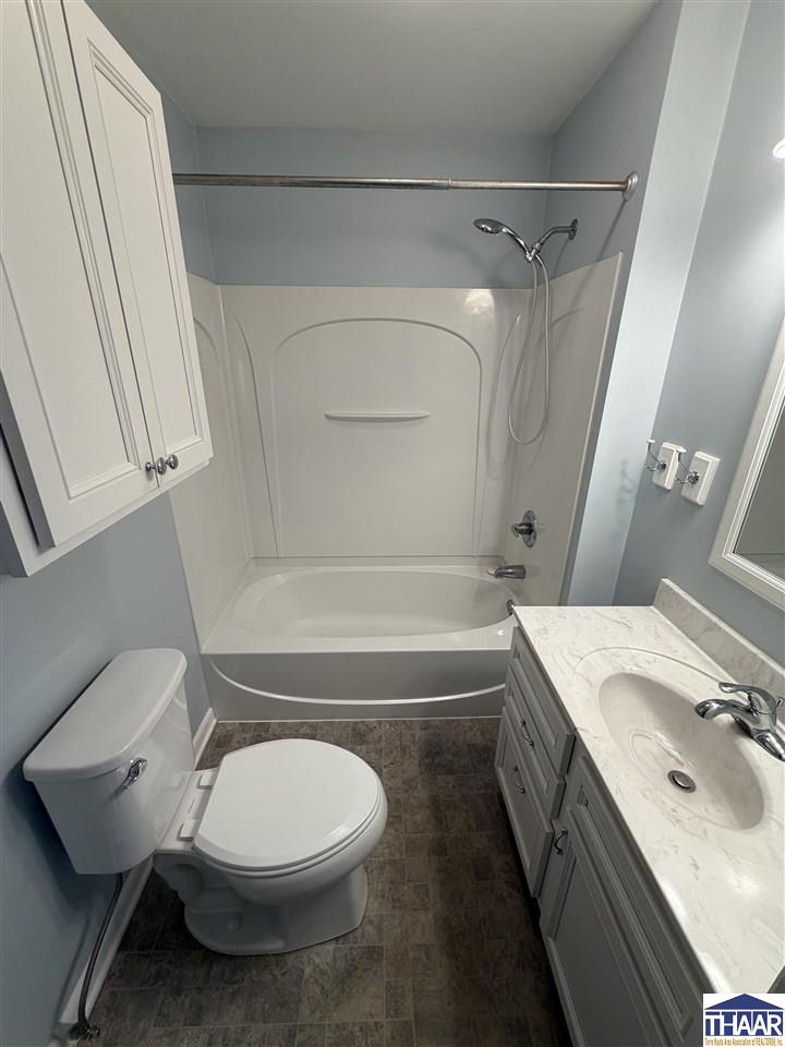 Bathroom with a tub-shower combination, toilet, and gray vanity with a marble-look countertop.