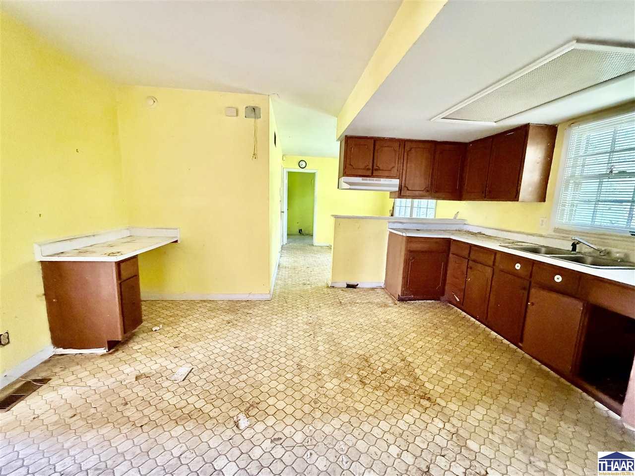 Vacant kitchen with dark wood cabinets, yellow walls, and patterned flooring.