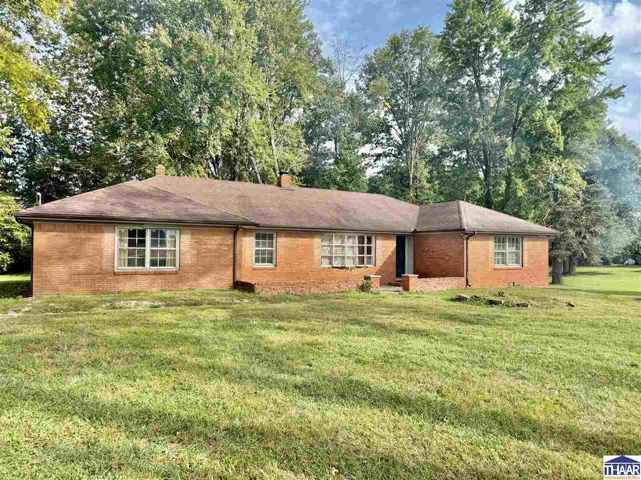 Red brick ranch house with a recessed entry, wide lawn, and mature trees.