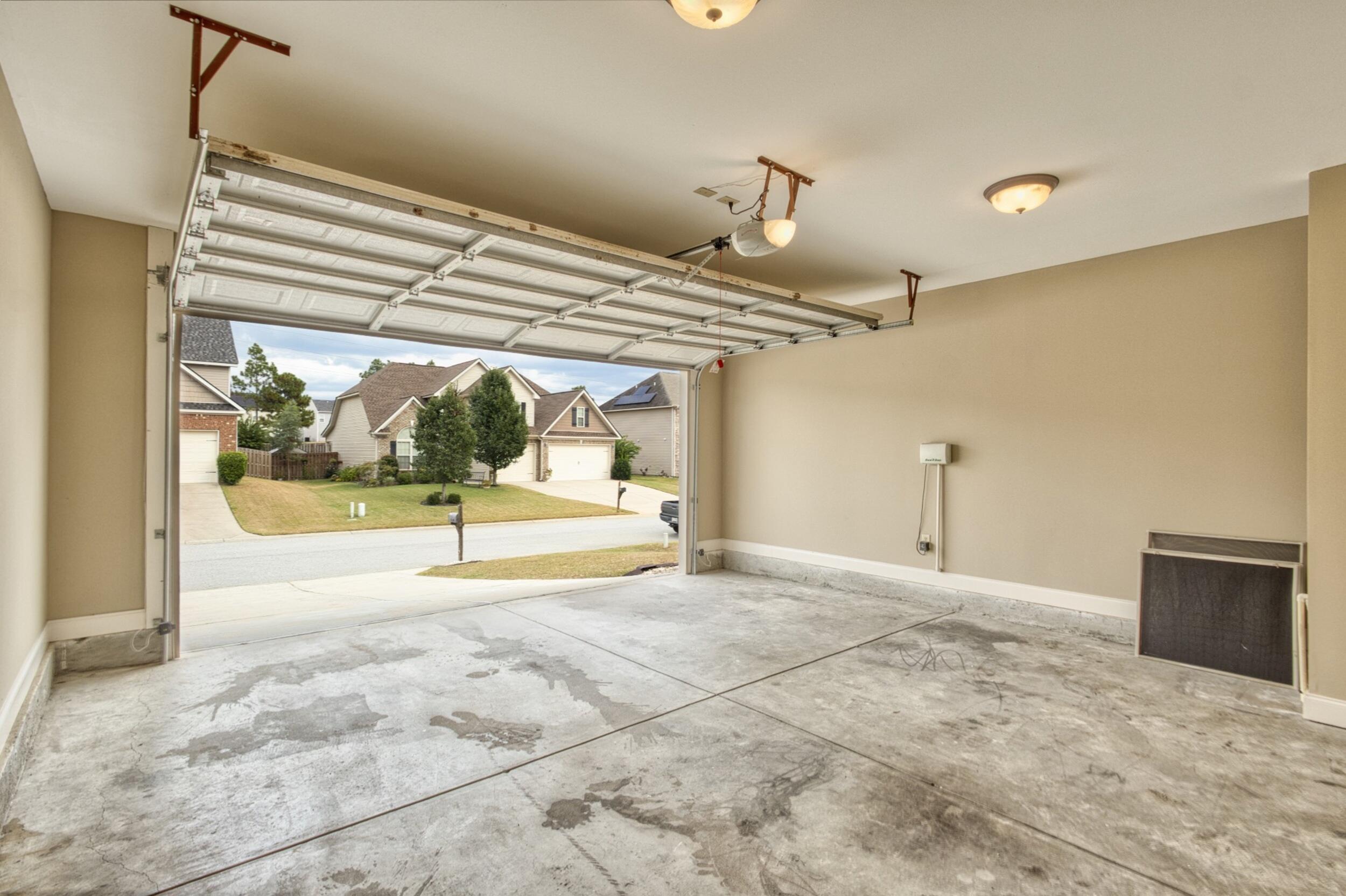 Empty garage with an open overhead door and stained concrete floor