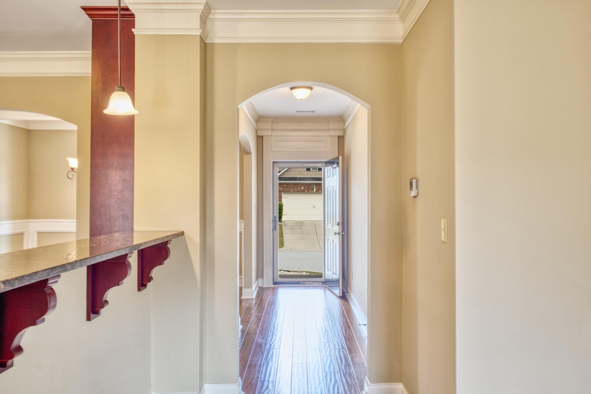 Entry foyer with a long tile floor, red bar counter, and open front door.