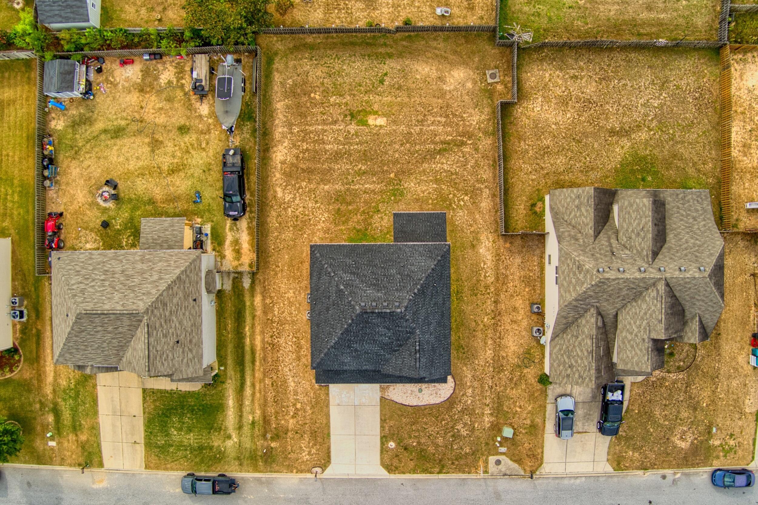 Aerial view of a single-story home with a dark roof and concrete driveway