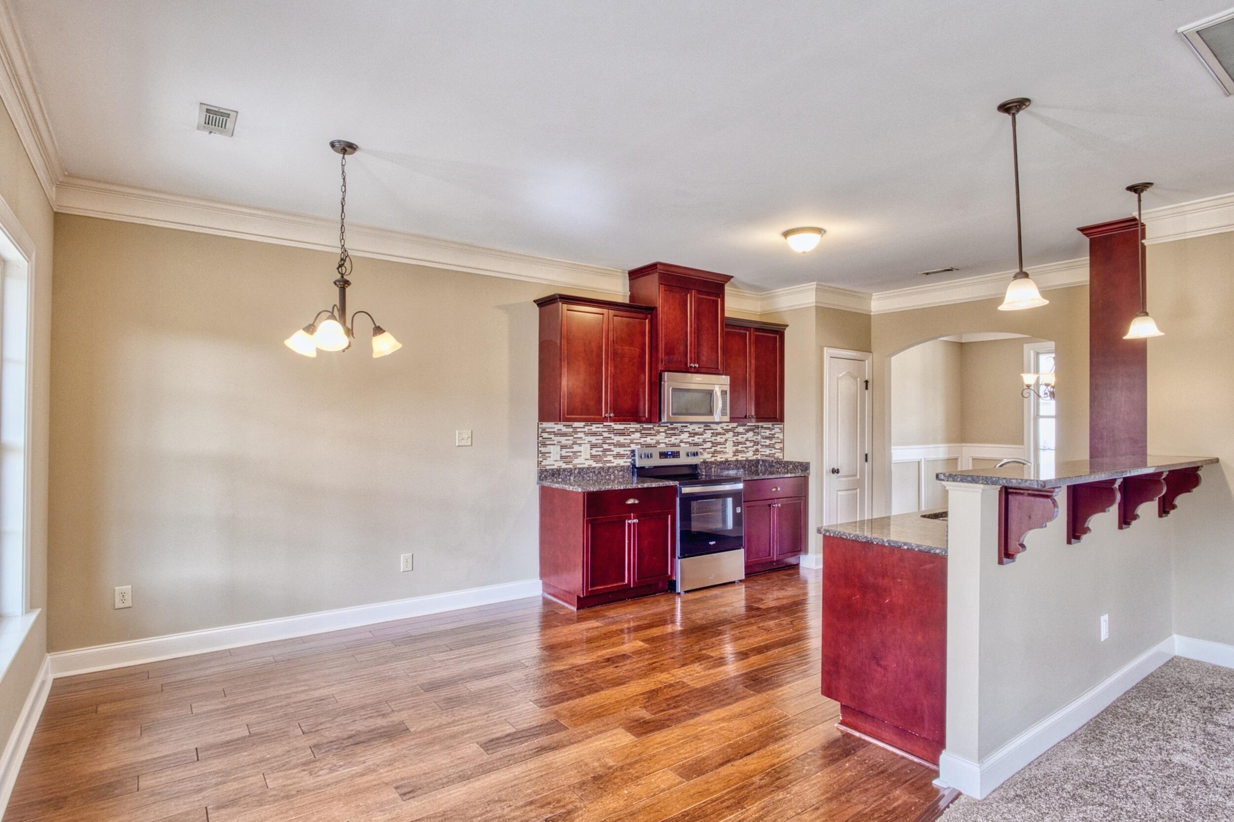 Open kitchen and dining area with cherry cabinets, stainless steel appliances, and a granite breakfast bar.