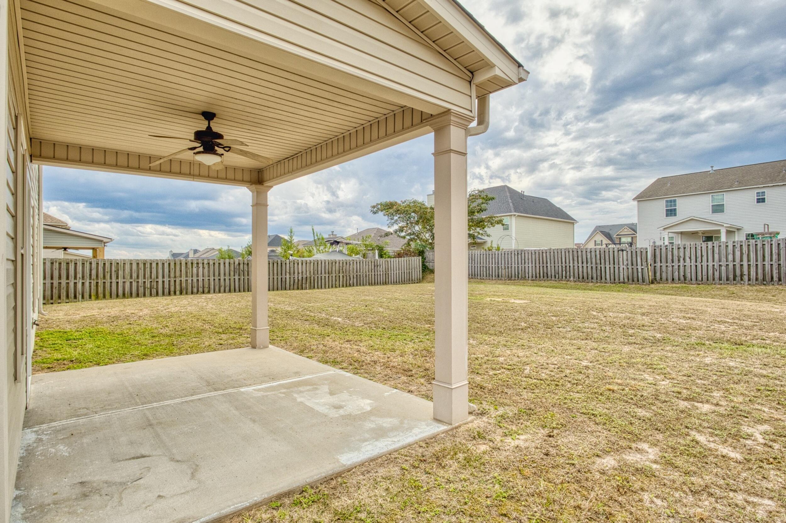 Covered patio with ceiling fan overlooking a fenced backyard.