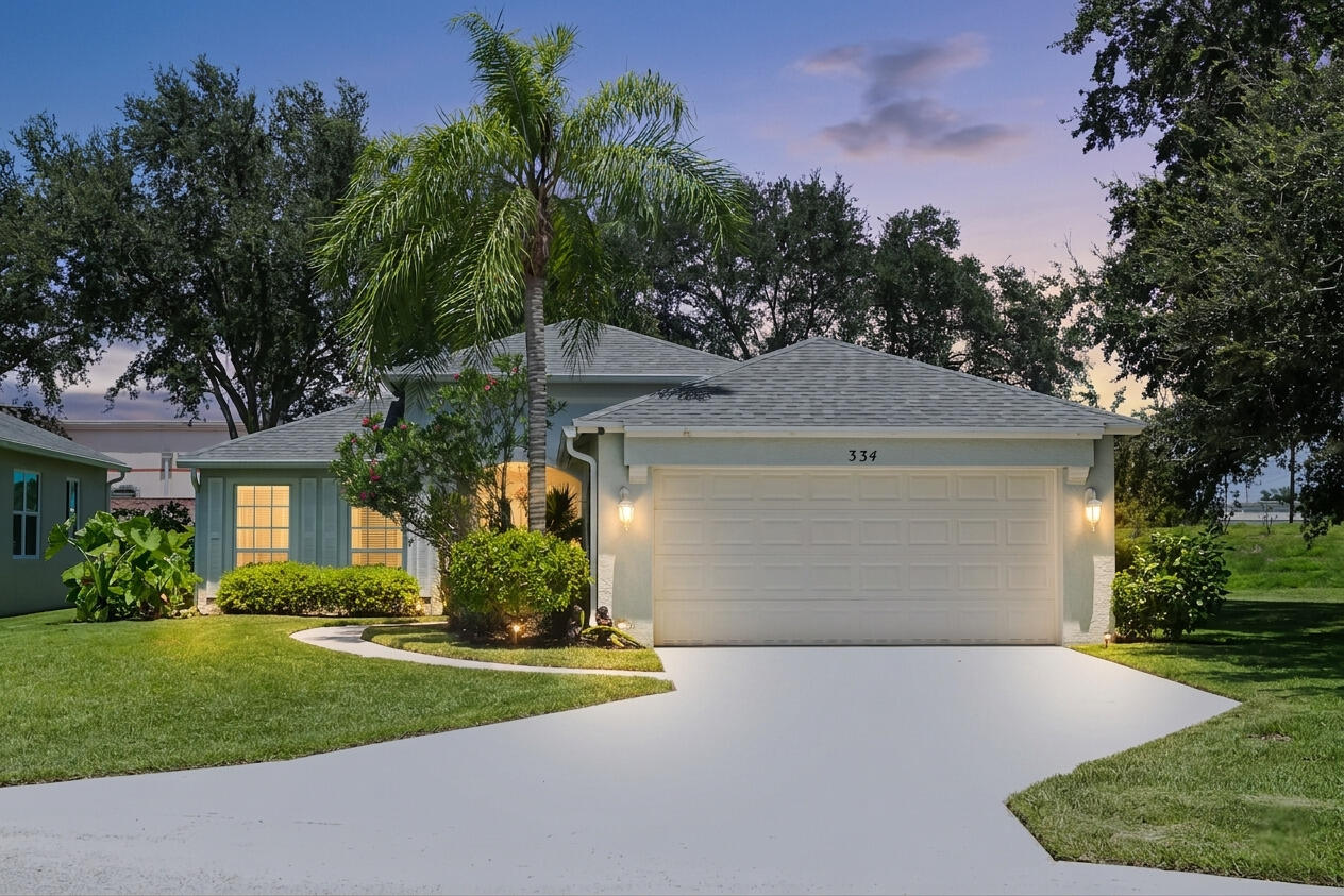 Single-story home with an attached garage, palm tree, and landscaped front yard at dusk.