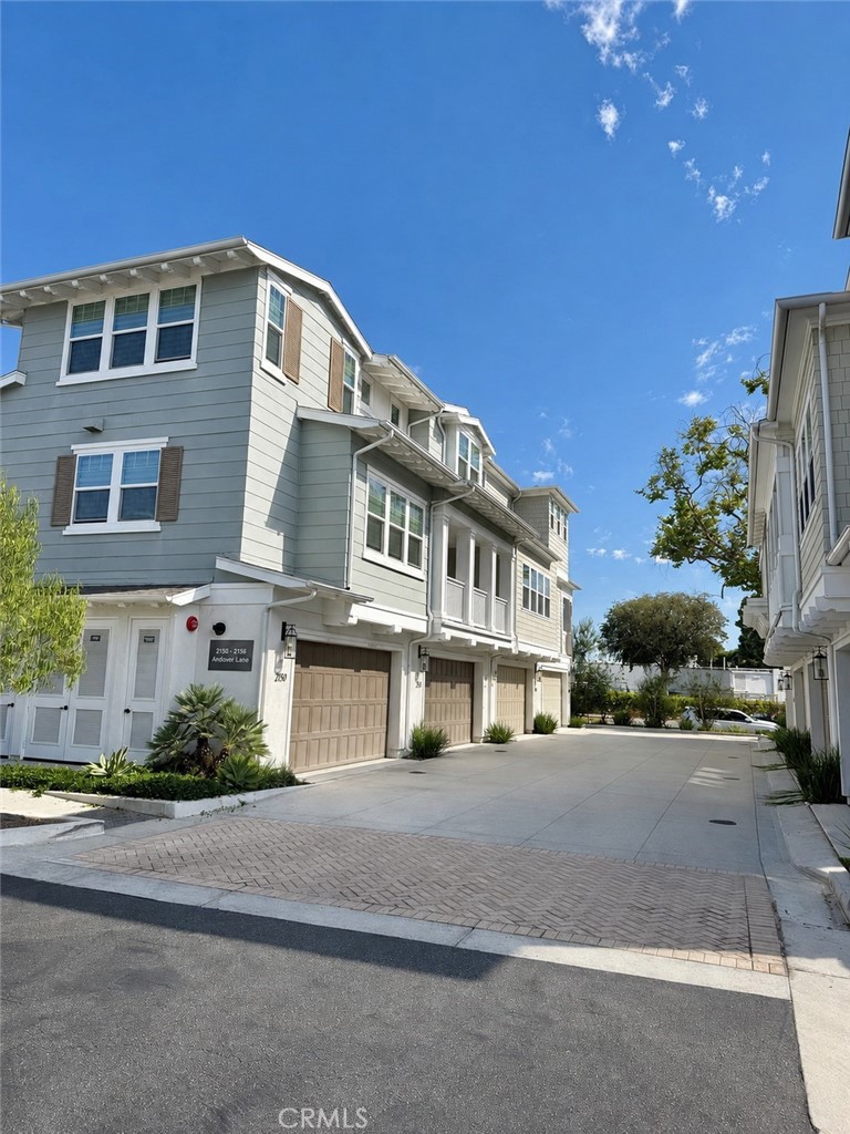 Attached gray homes with white trim and garage doors along a shared driveway.