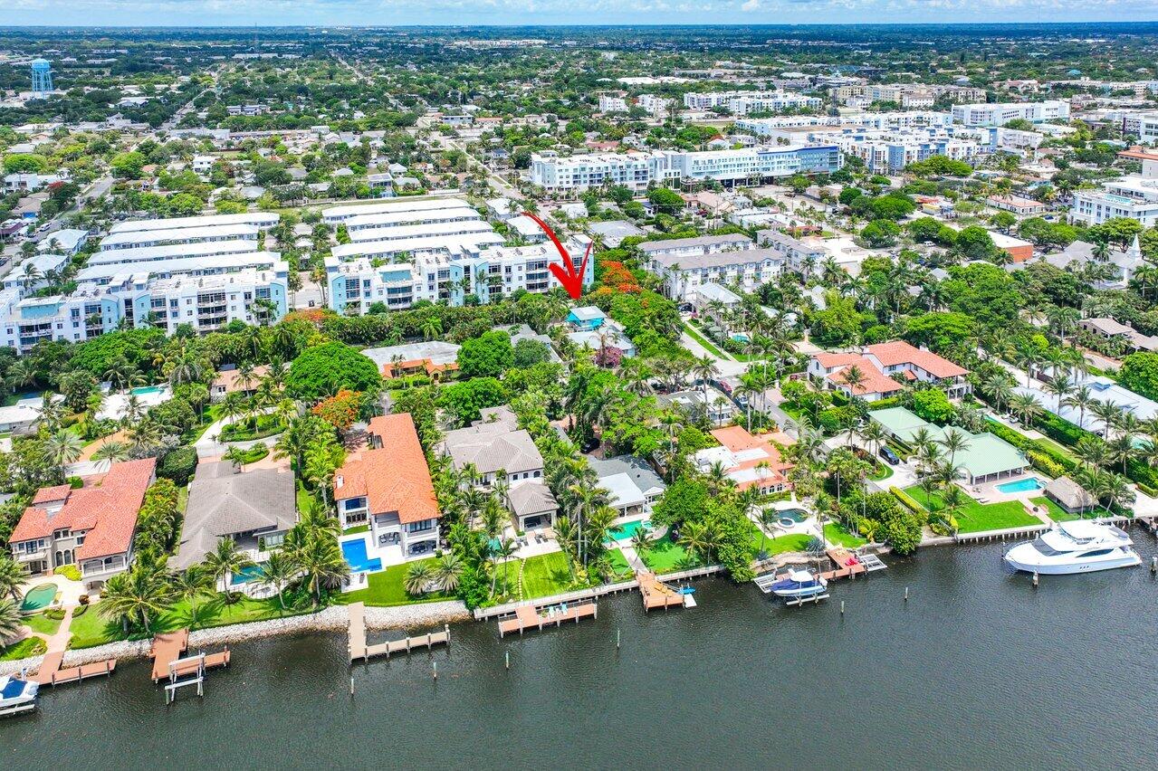Aerial view of a waterfront neighborhood, with a red arrow marking a property near the canal.