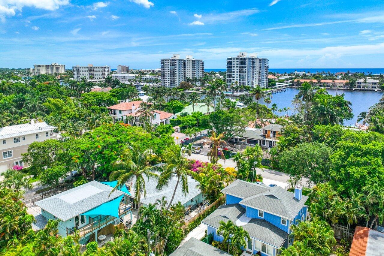 Aerial view of Delray Beach homes, a palm-lined waterway, and the ocean horizon.