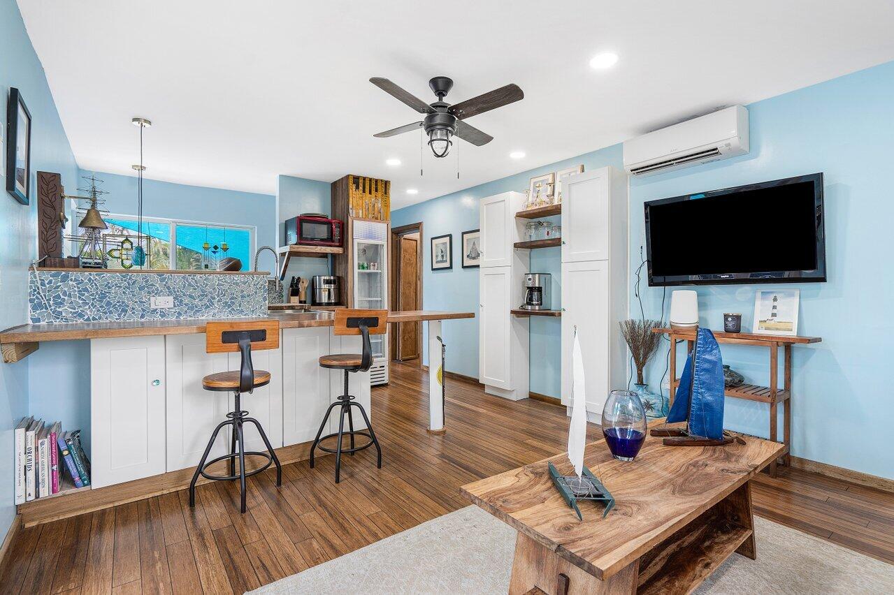 Living area with blue walls, bar seating, built-in shelves, and nautical decor on a wood coffee table.