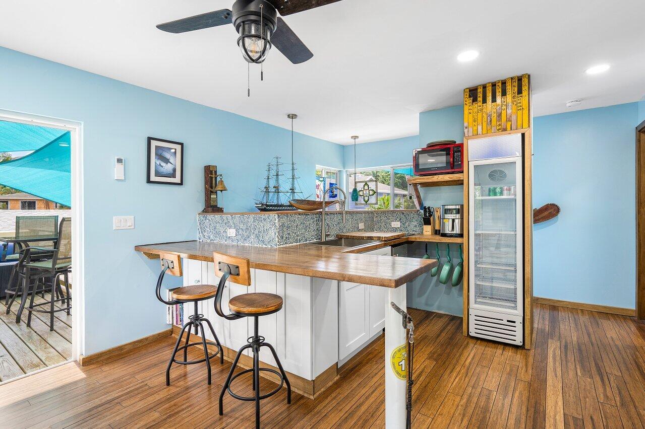 Kitchen with a large wood-topped island, bar stools, patterned tile backsplash, and glass-front beverage refrigerator.