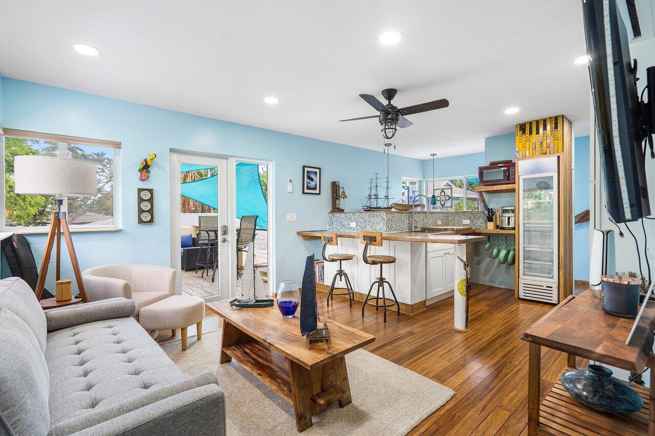Open living room and kitchen with a bar island, wood floors, and sliding doors to a patio.