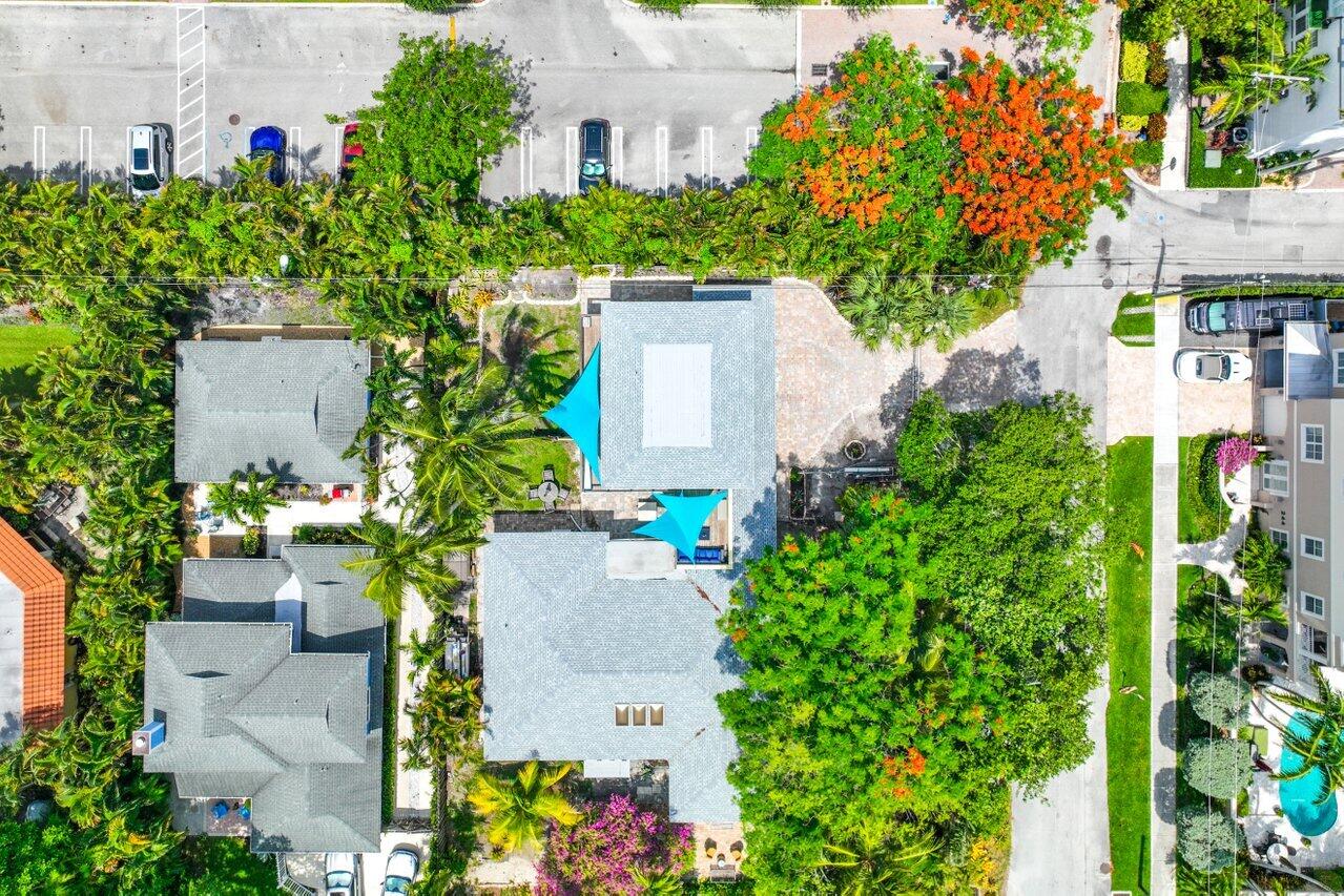 Aerial view of a home with a turquoise pool amid dense tropical landscaping.