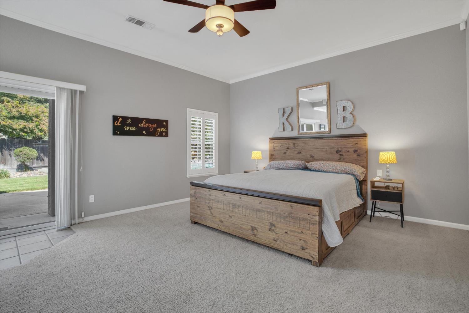 Bedroom with a rustic wood bed and sliding glass door opening toward the backyard.