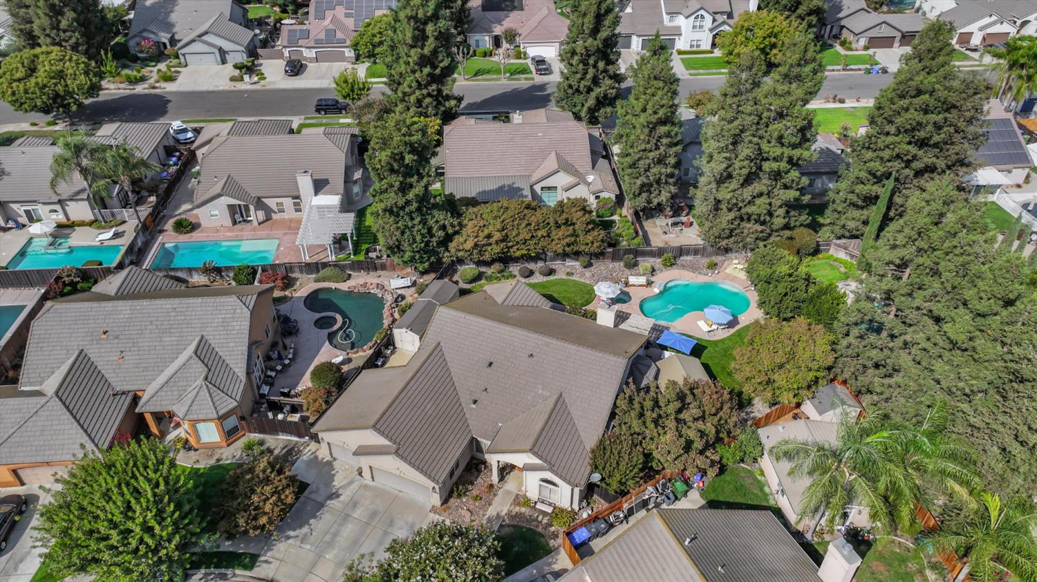 Aerial view of homes and landscaped yards, with several backyard pools and solar panels.