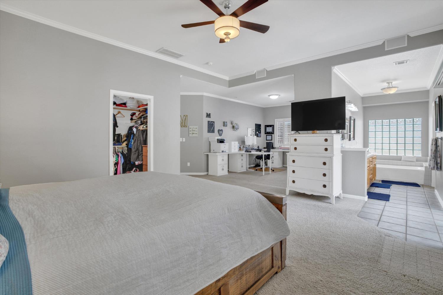 Primary bedroom with a large bed, office desk, and tiled soaking-tub area.