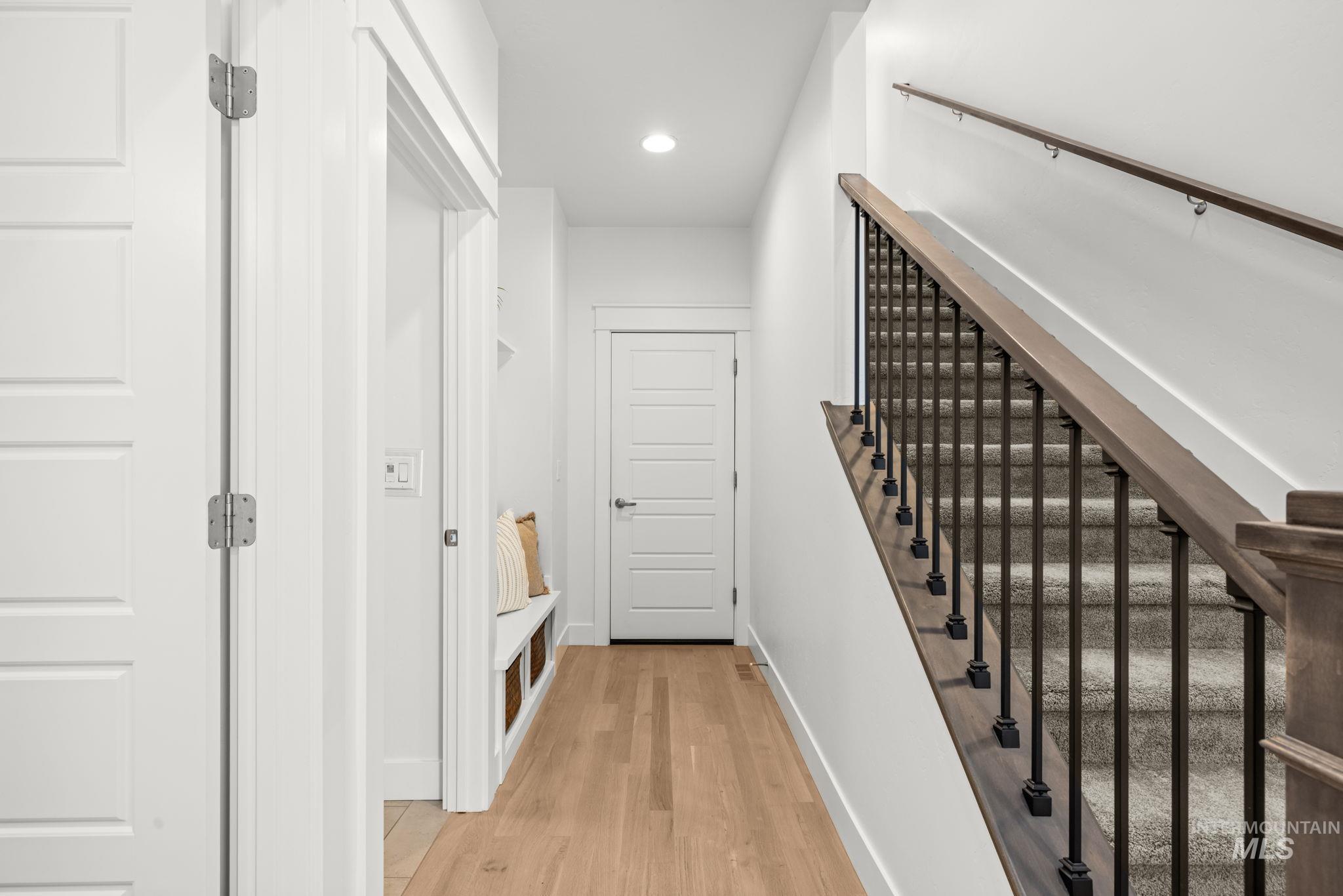 Entry hallway with a built-in bench and carpeted staircase with dark metal railing