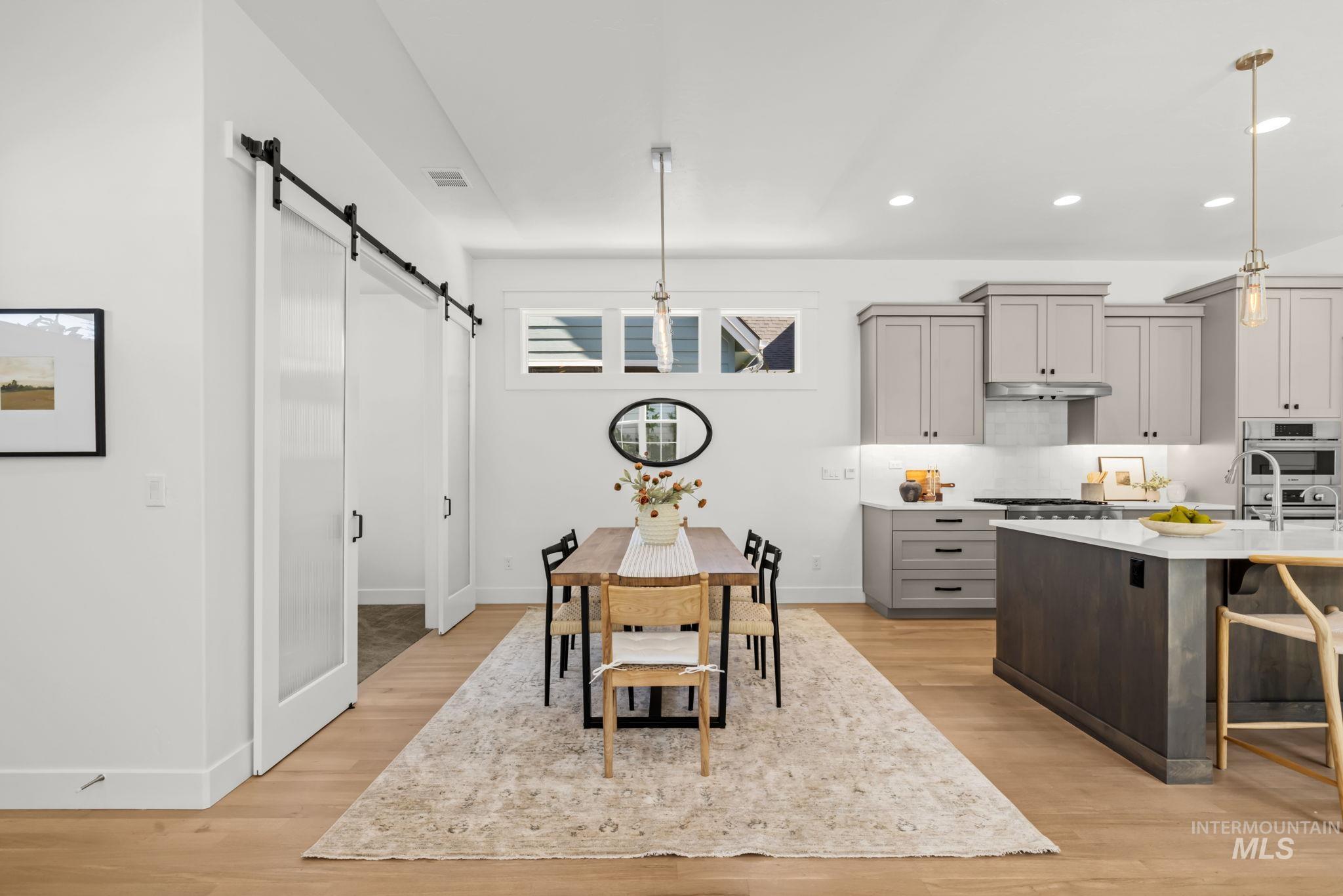 Dining area and kitchen with a barn-style sliding door, gray cabinetry, and a large island.