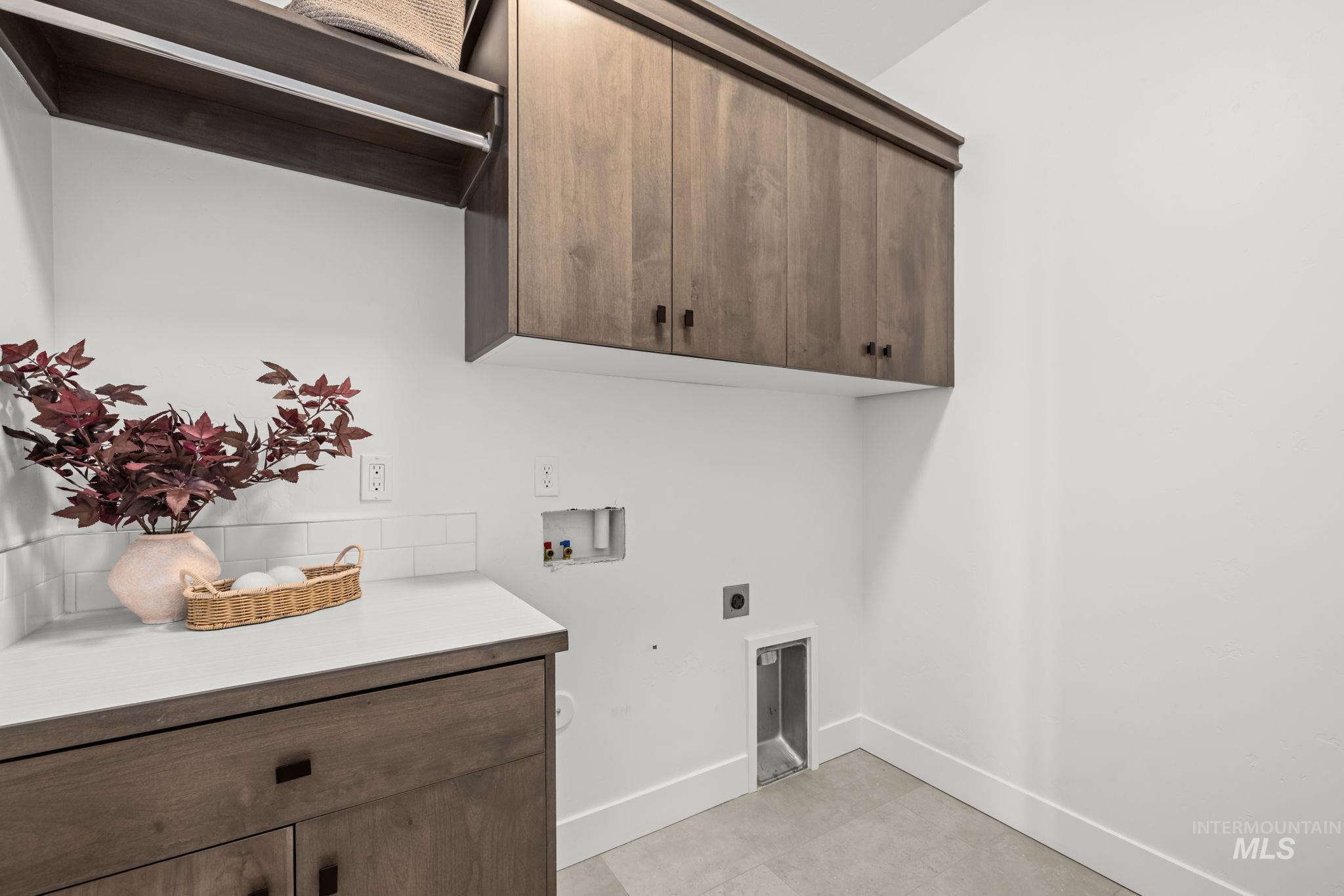Laundry room with dark wood cabinets, countertop, and washer and dryer hookups.