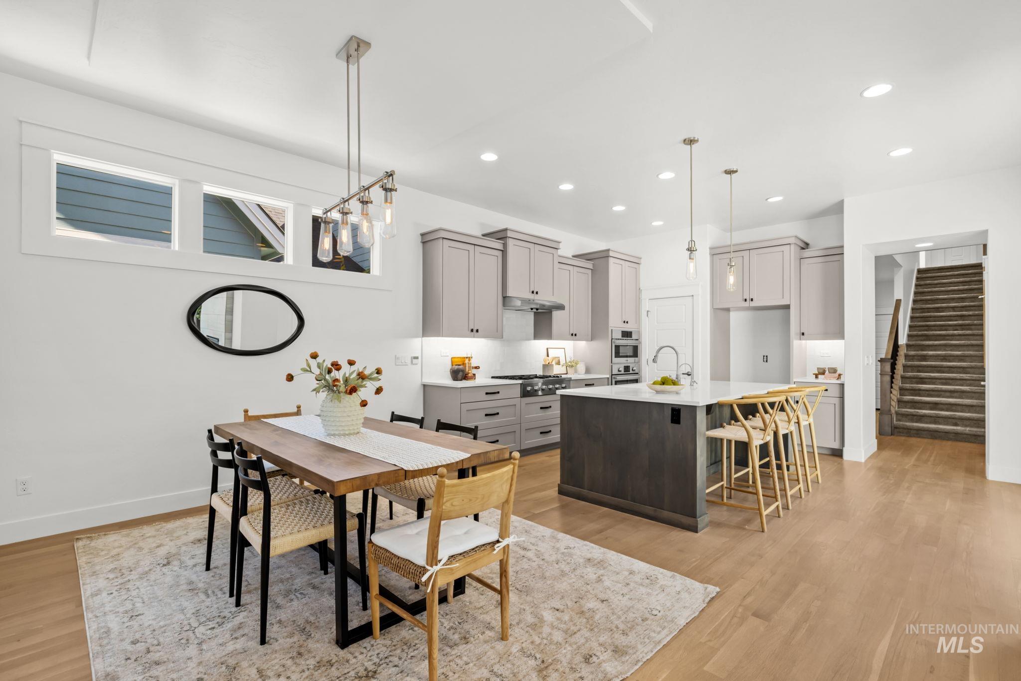 Open-plan kitchen and dining area with a dark island, gray cabinets, and a wood dining table.