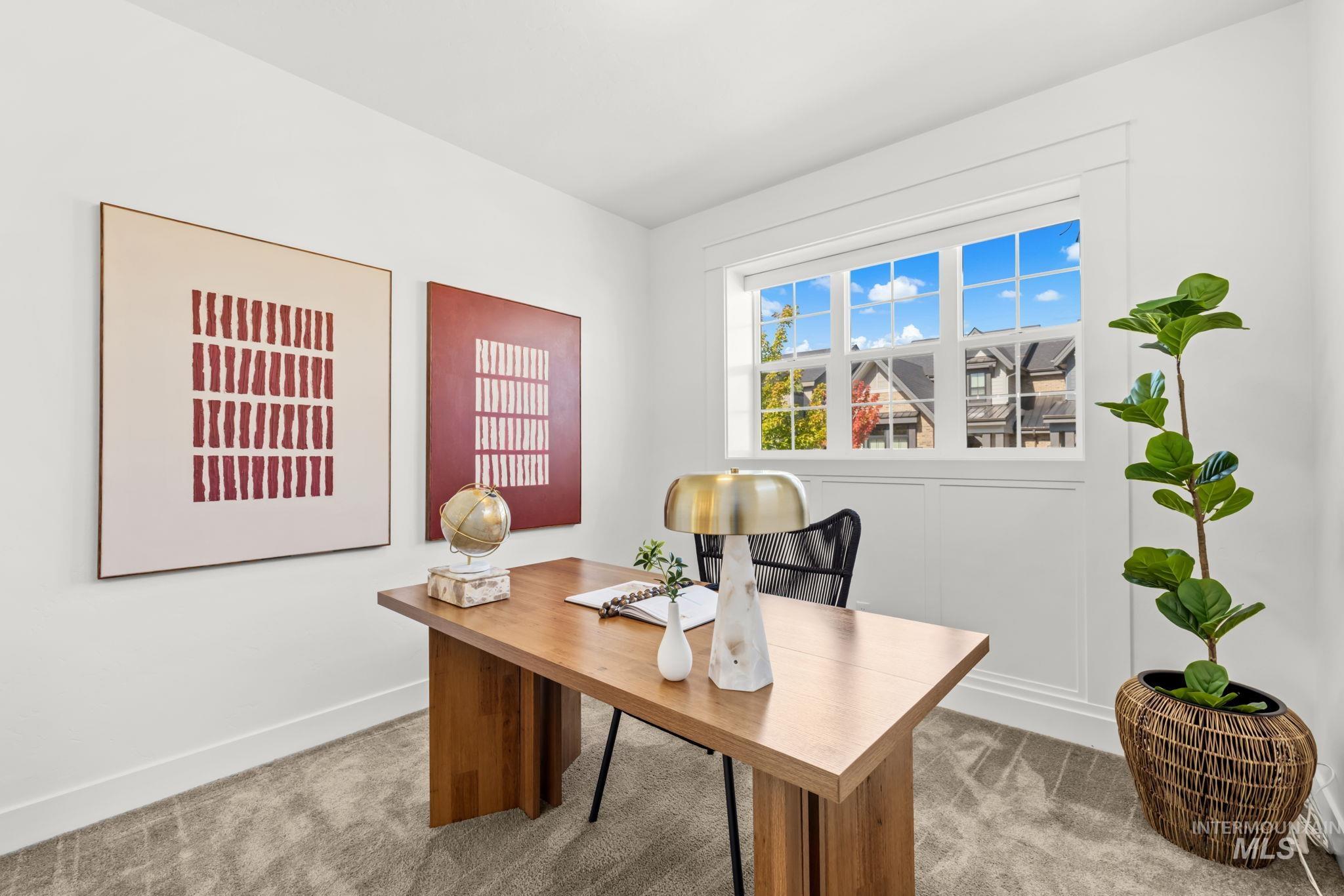 Staged home office with a wooden desk and large window overlooking neighboring homes.
