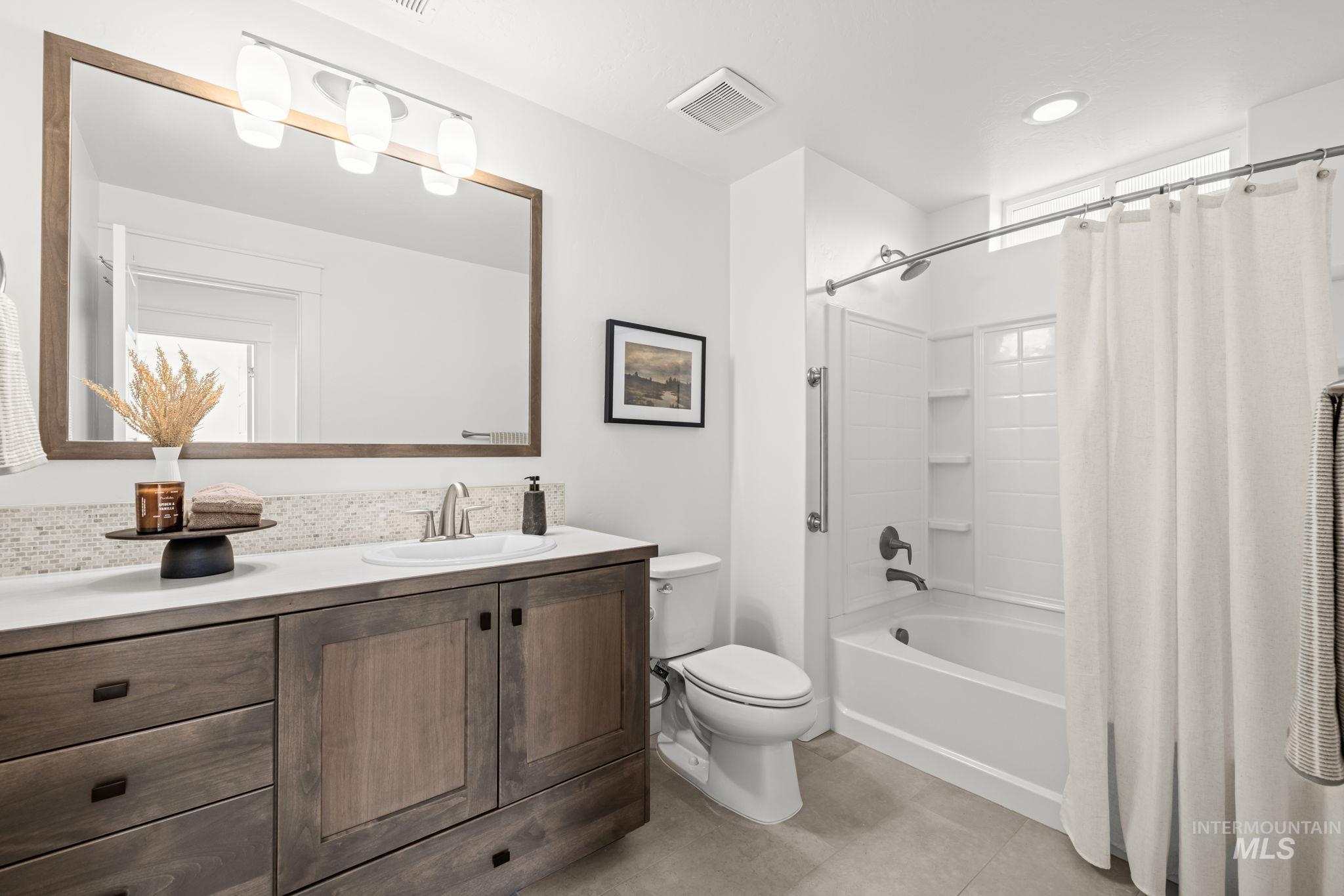 Bathroom with a dark wood vanity, large framed mirror, and white tub-shower.