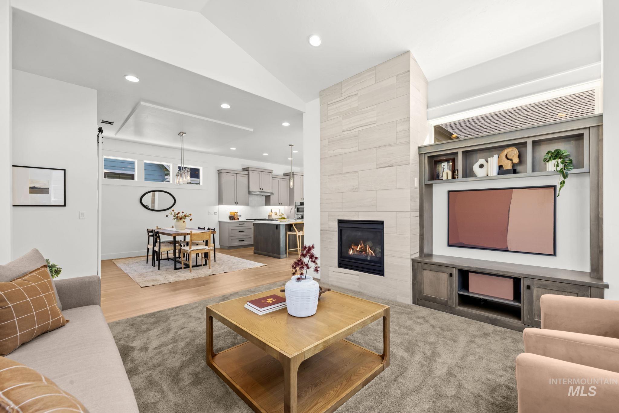 Open-plan living room with a tiled fireplace, built-in media shelves, and dining area beside the kitchen.