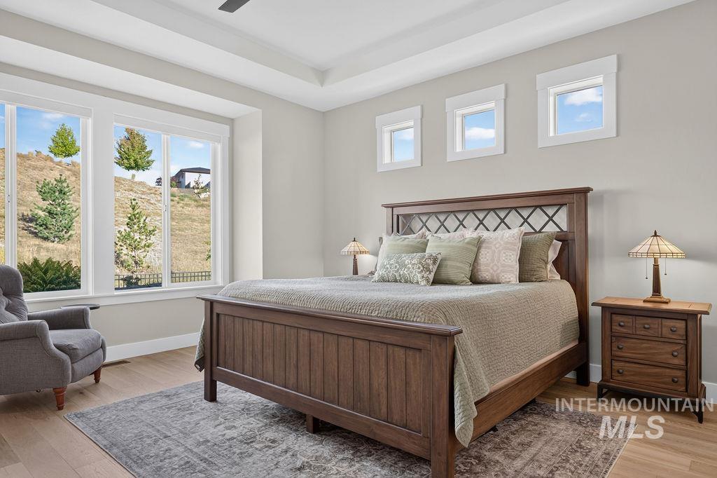 Furnished bedroom with a dark wood bed, tall windows, and views of a grassy hillside.