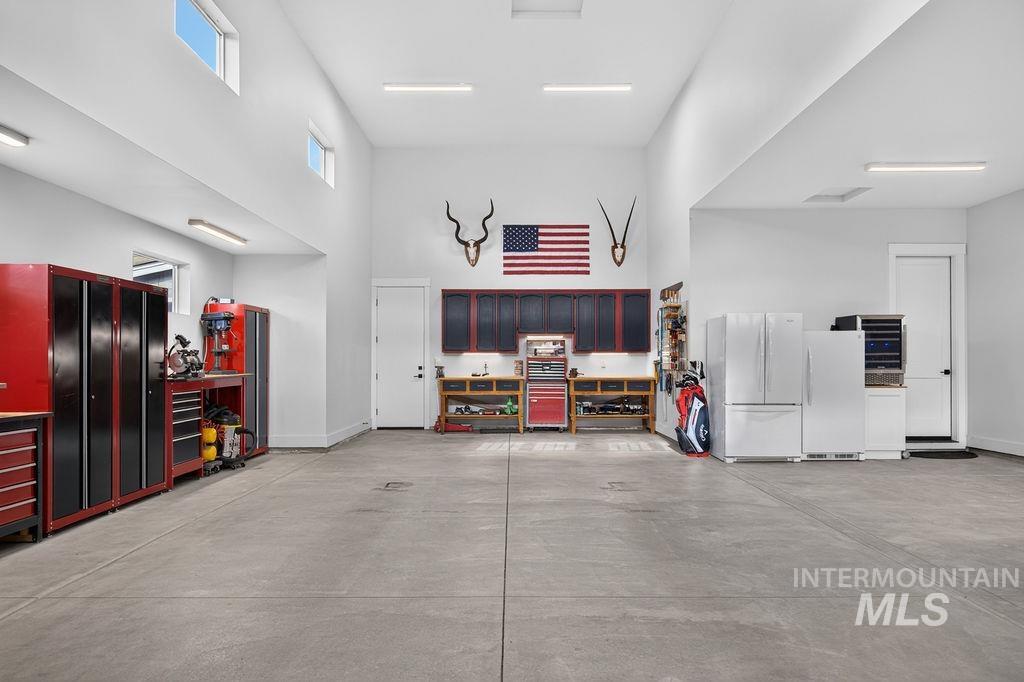 Spacious garage with red tool cabinets, workbenches, and an American flag above the back wall.