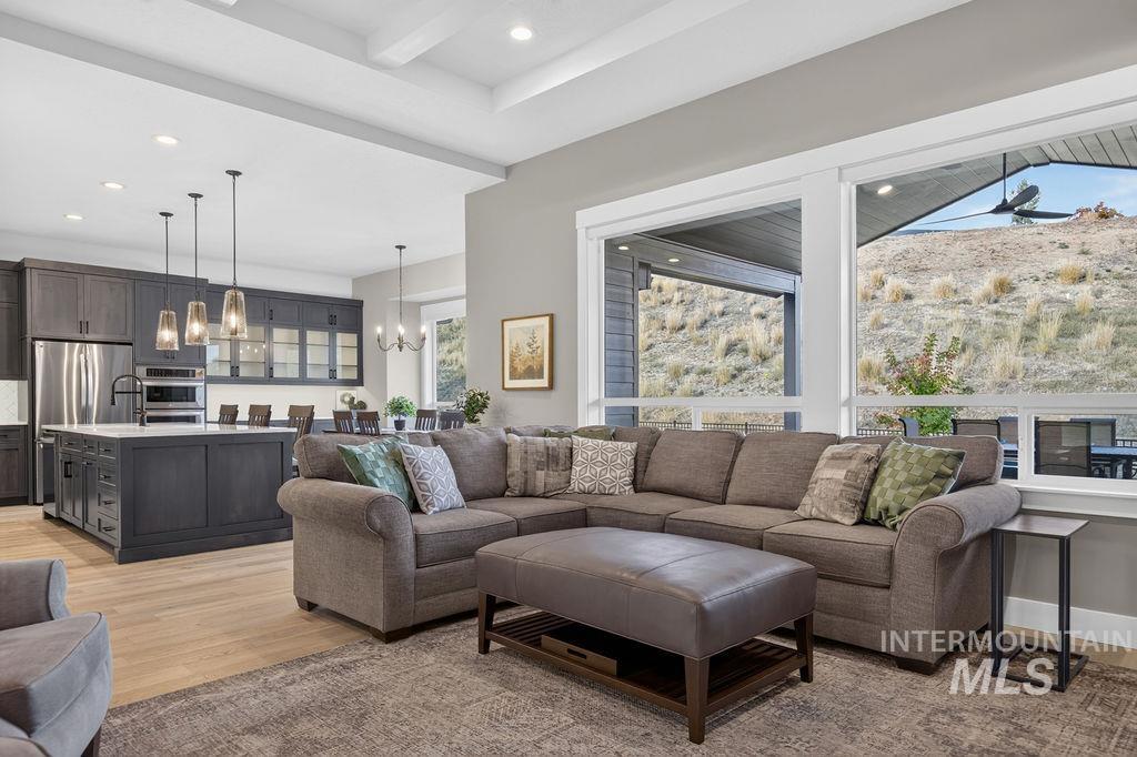 Open-plan living room with a gray sectional and large windows overlooking a dry hillside.