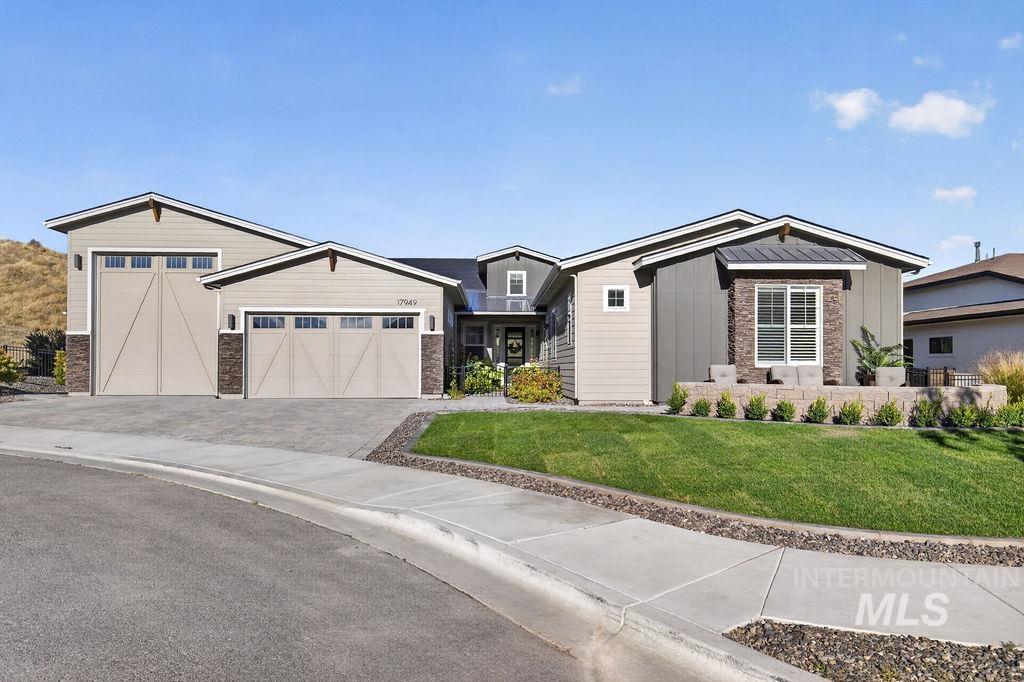Modern gray home with two garage doors, stone accents, and a landscaped front lawn.