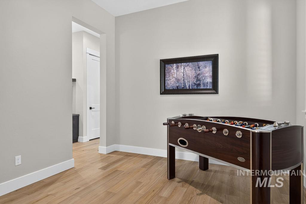 Game room with a foosball table, light wood flooring, and a framed woodland picture.