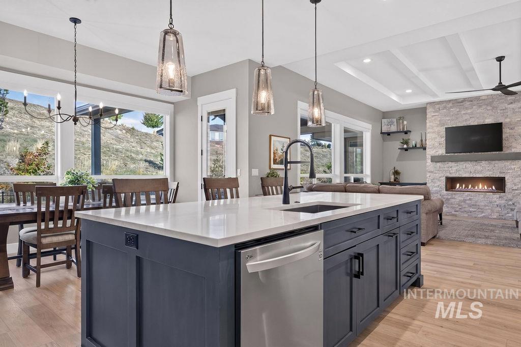 Open-plan kitchen with a large gray island, dining table, and stone fireplace.