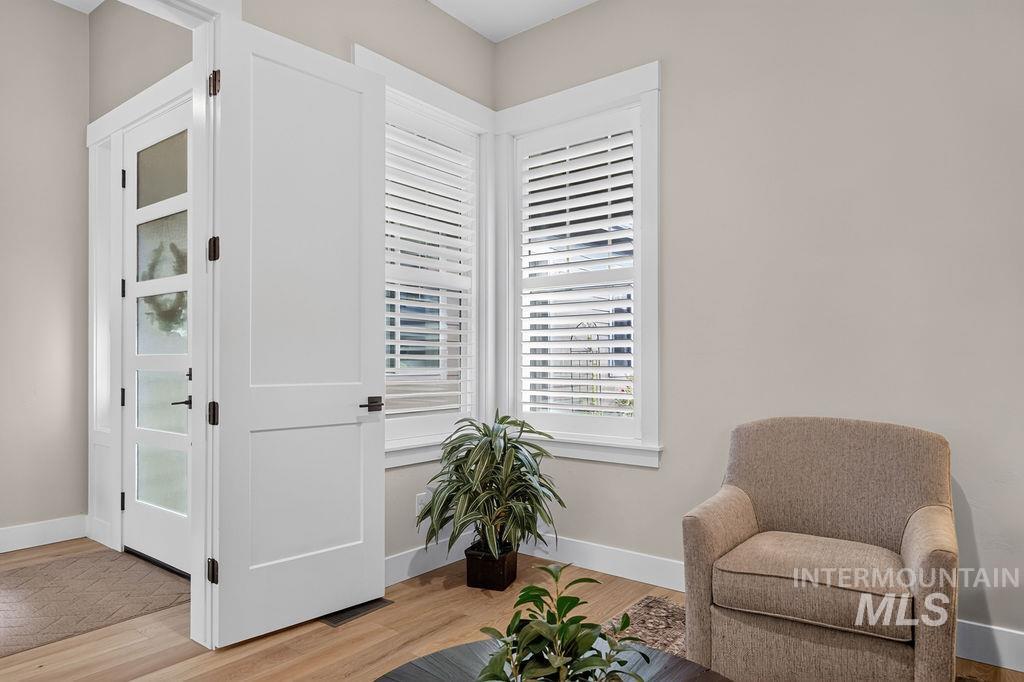 Entryway with a glass-panel front door, plantation shutters, and a beige armchair.