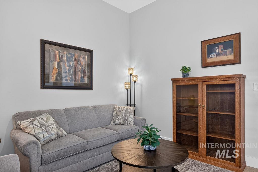 Living room with a gray sofa, round wooden coffee table, and glass-front wooden cabinet.