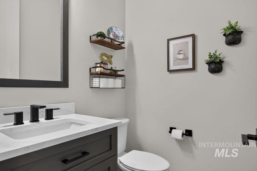 Bathroom with a dark vanity, white sink, black fixtures, and decorative wall shelves.