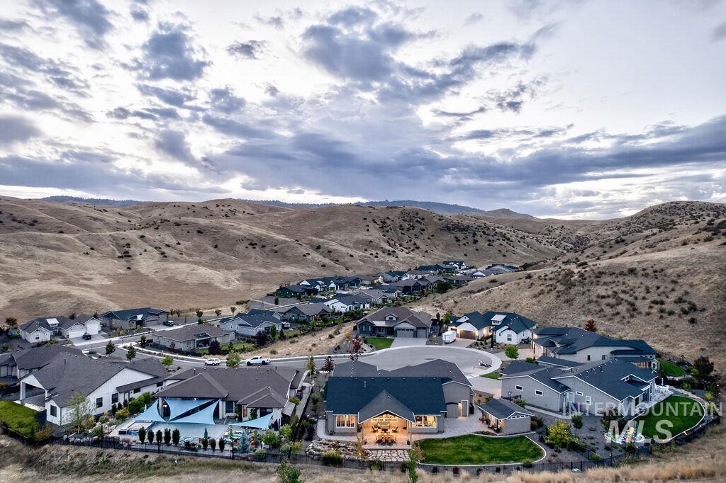 Aerial view of a home at the edge of a neighborhood beneath rolling hills.