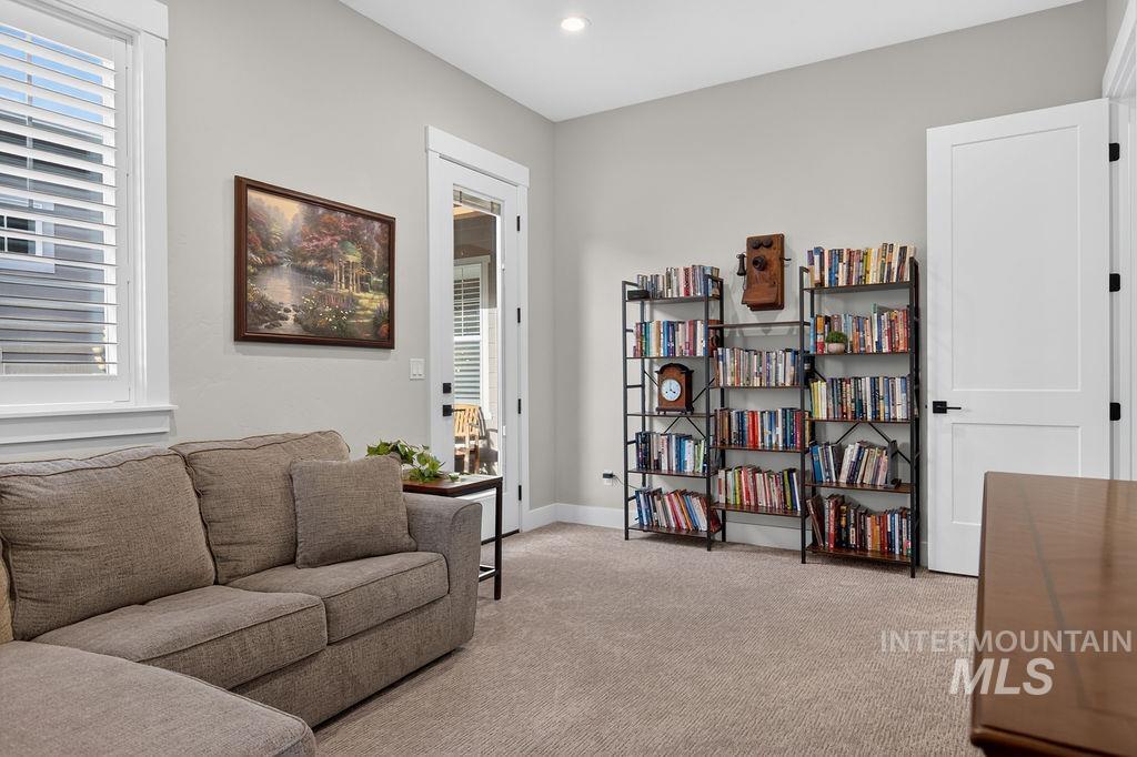 Furnished den with book-filled shelves, a beige sofa, and plantation shutters.