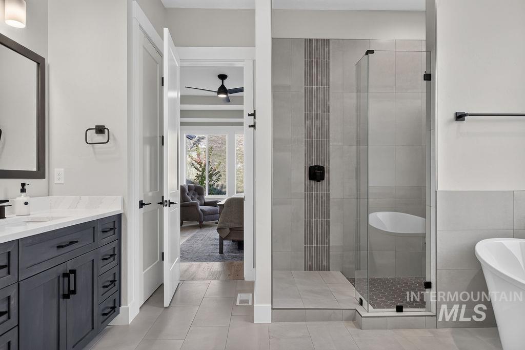 Modern bathroom with a dark vanity, glass-enclosed tiled shower, and freestanding tub.