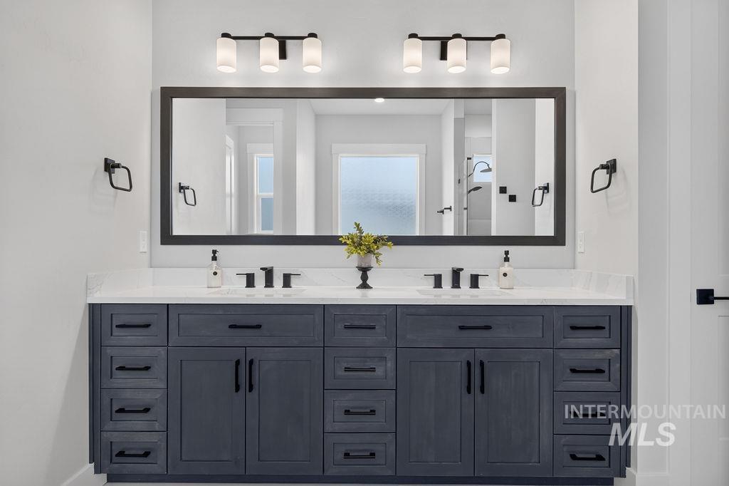 Bathroom with a dark double vanity, white countertop, black faucets, and oversized framed mirror.