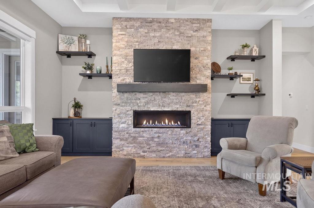 Living room with a stone fireplace, mounted television, and dark blue built-in cabinets.
