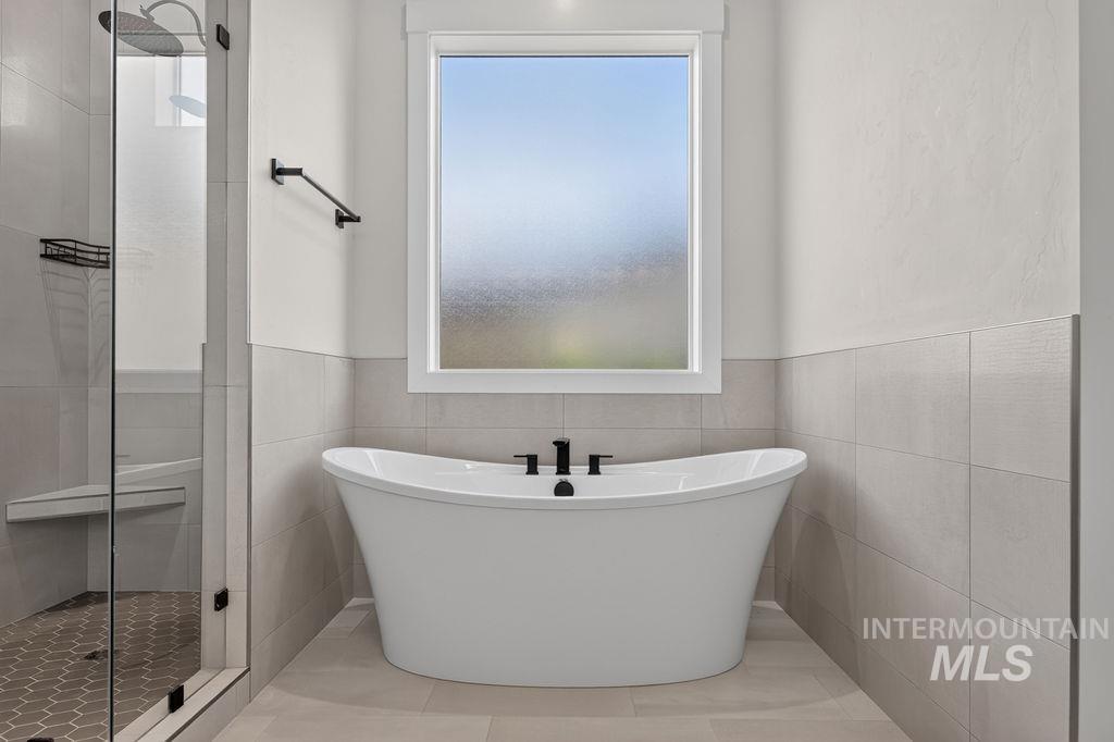 Bathroom with a freestanding tub beneath a frosted window and a glass-enclosed shower.