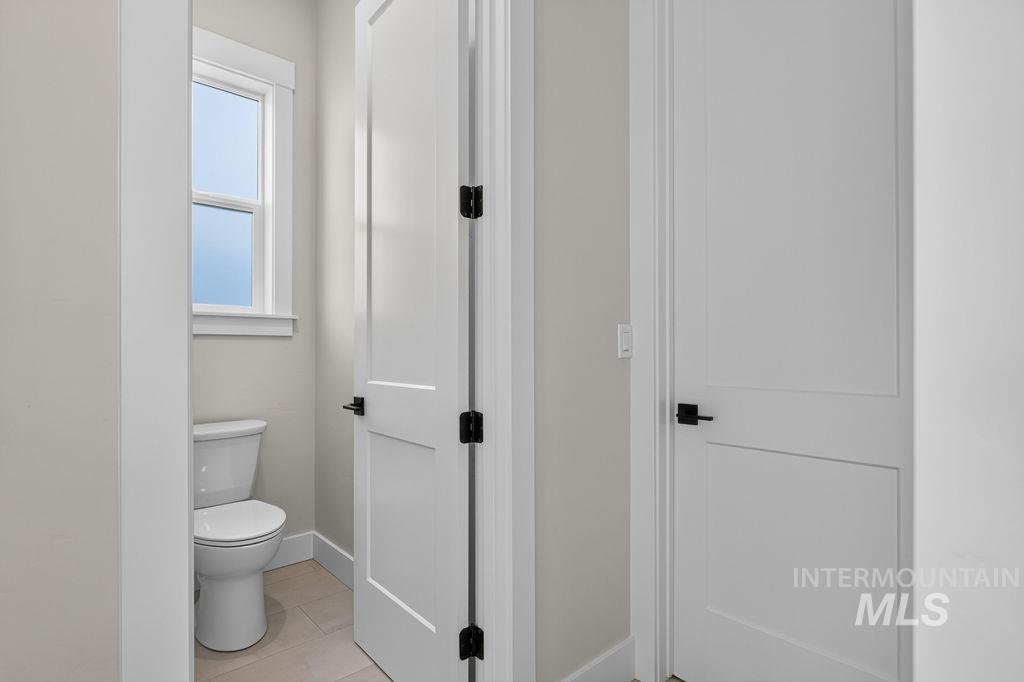 Small bathroom with a toilet beneath a window, seen through an open door.