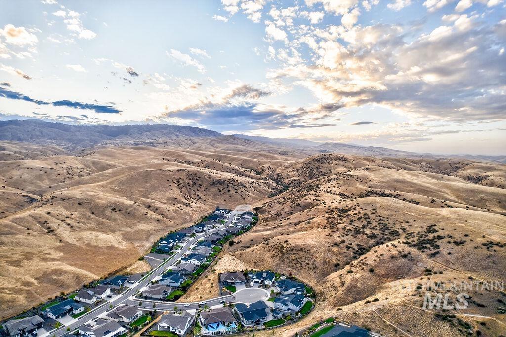 Aerial view of homes winding through rolling hills beneath a sunset sky.