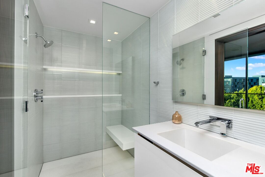 Modern bathroom with a glass shower, built-in bench, and white floating vanity.