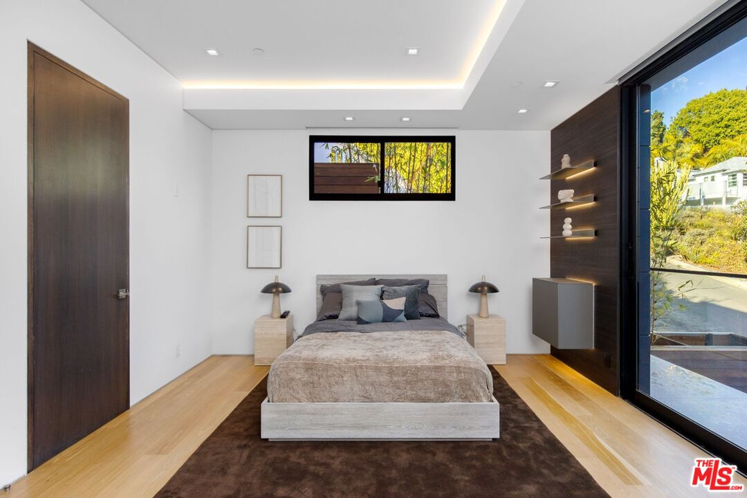 Modern bedroom with a low bed, wood floors, and a large sliding glass door.